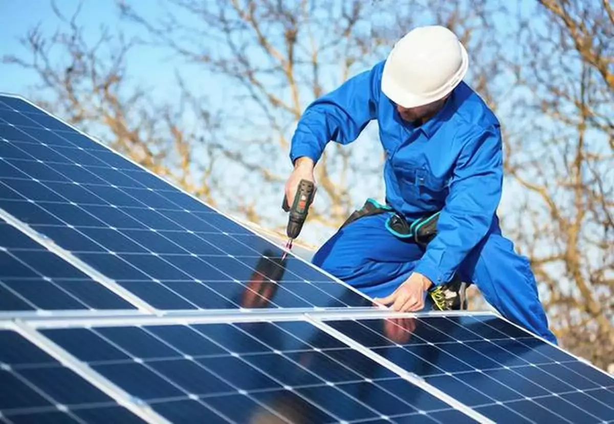 Worker installing solar panels on roof